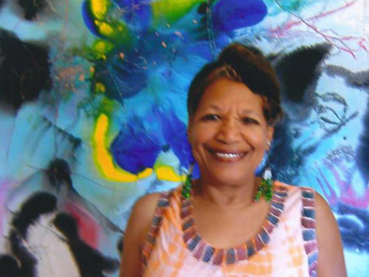 A woman smiles in front of an abstract painting.