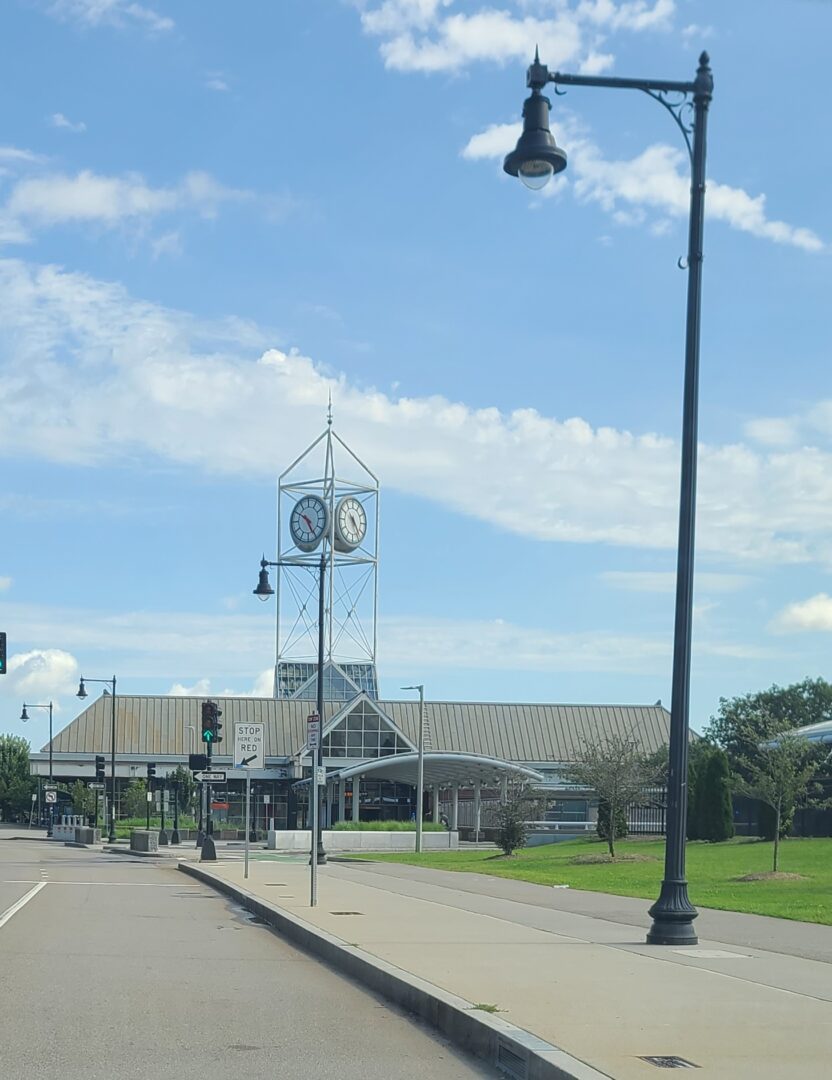 A street light and clock tower on the side of a road.